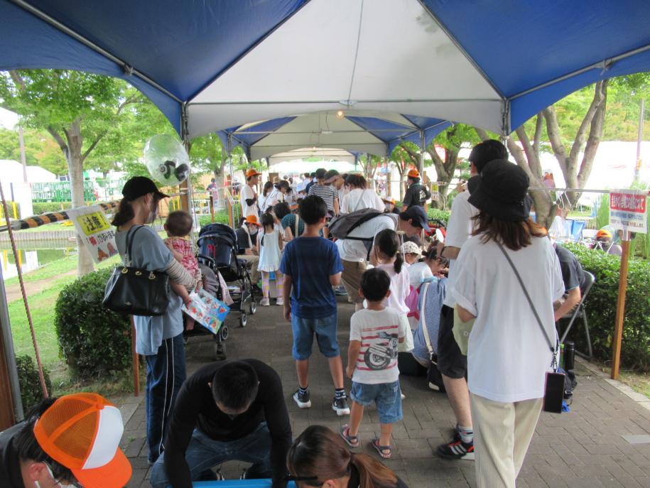 行船公園のテント下で金魚すくいの受付を待つ家族連れの過去開催公式写真
