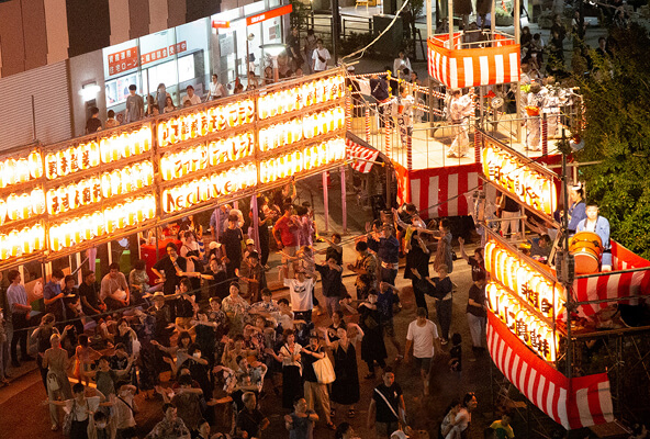 夜の盆踊り会場で提灯の下に人が集まっている自由が丘納涼盆踊り大会の公式写真