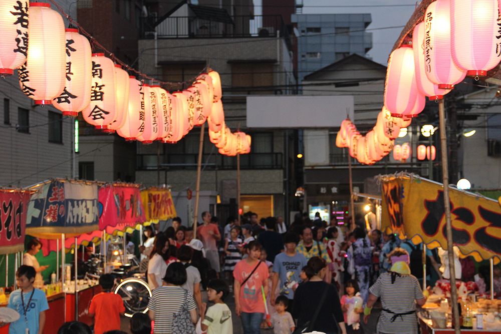 2019年の天妙国寺盆踊り。提灯の下に屋台が並び、親子連れなど多くの来場者が旧東海道側を歩いている