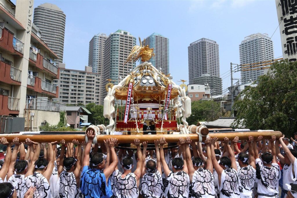 高層マンションを背に担ぎ上げられる佃祭の八角神輿