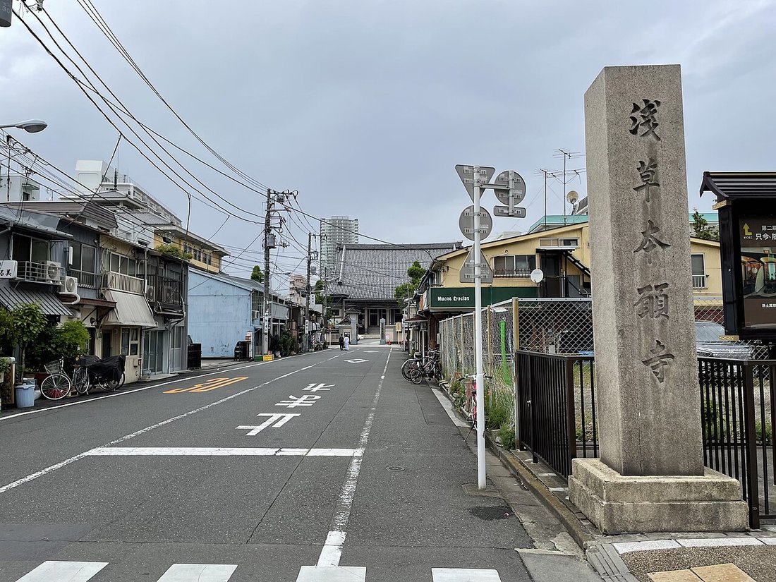 東本願寺の参道入口。歩道に「浅草本願寺」と刻まれた石柱が立ち、その奥に瓦屋根の本堂が見える