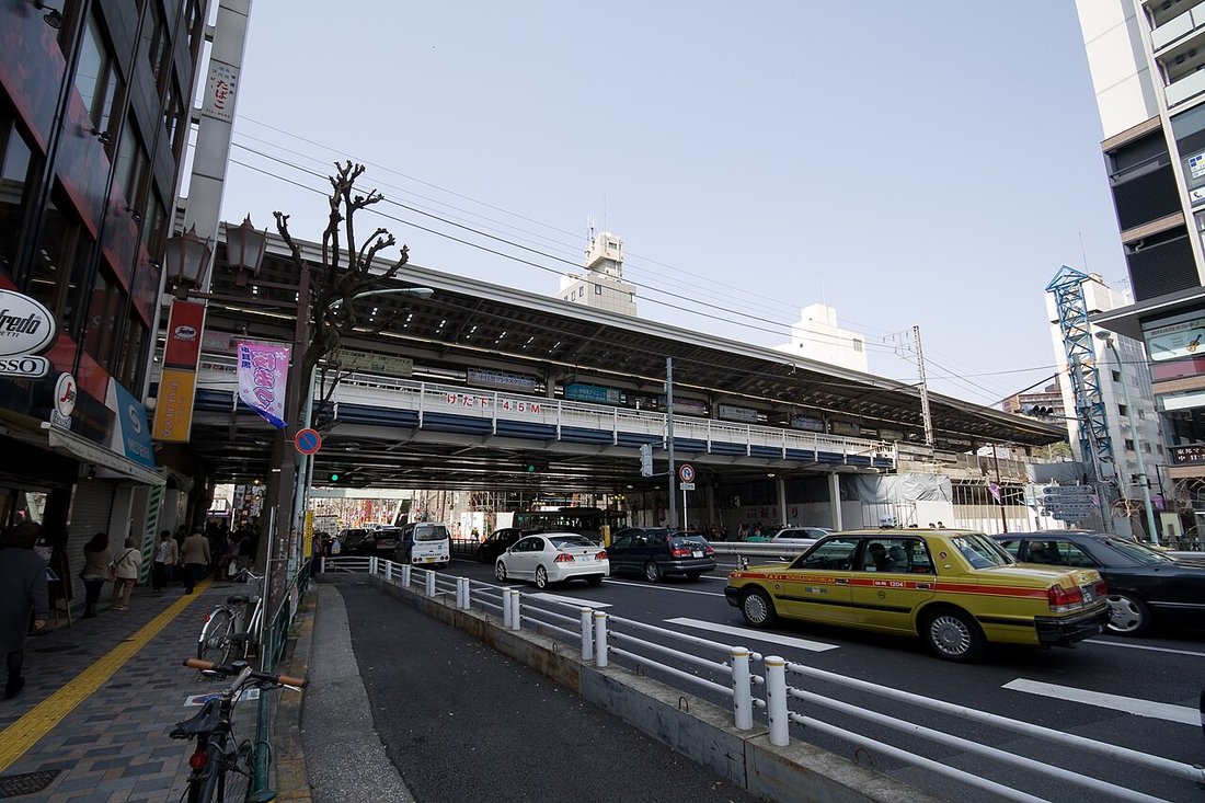 東急東横線・東京メトロ日比谷線 中目黒駅の高架駅舎と山手通り。手前をタクシーが走り、歩道に人が歩いている