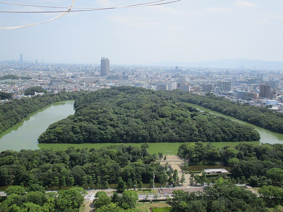 気球の上空から見た仁徳天皇陵古墳と堺の街並み。手前に濠と森、奥にビル群が広がる