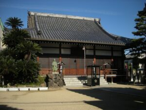大阪市此花区の伝法山西念寺の本堂と、前庭に立つ僧形の石像